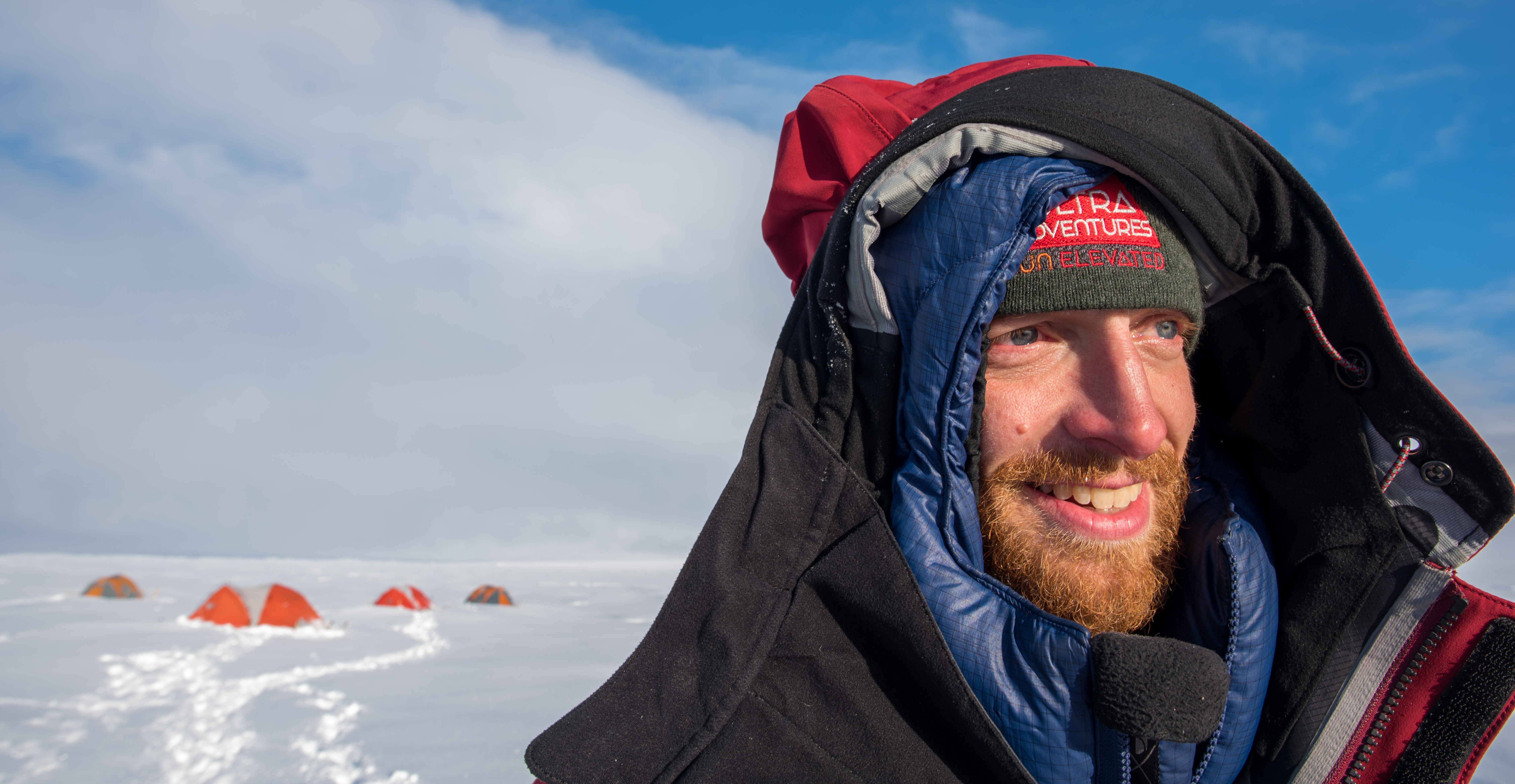 A man wearing a winter coat stands on an ice sheet.