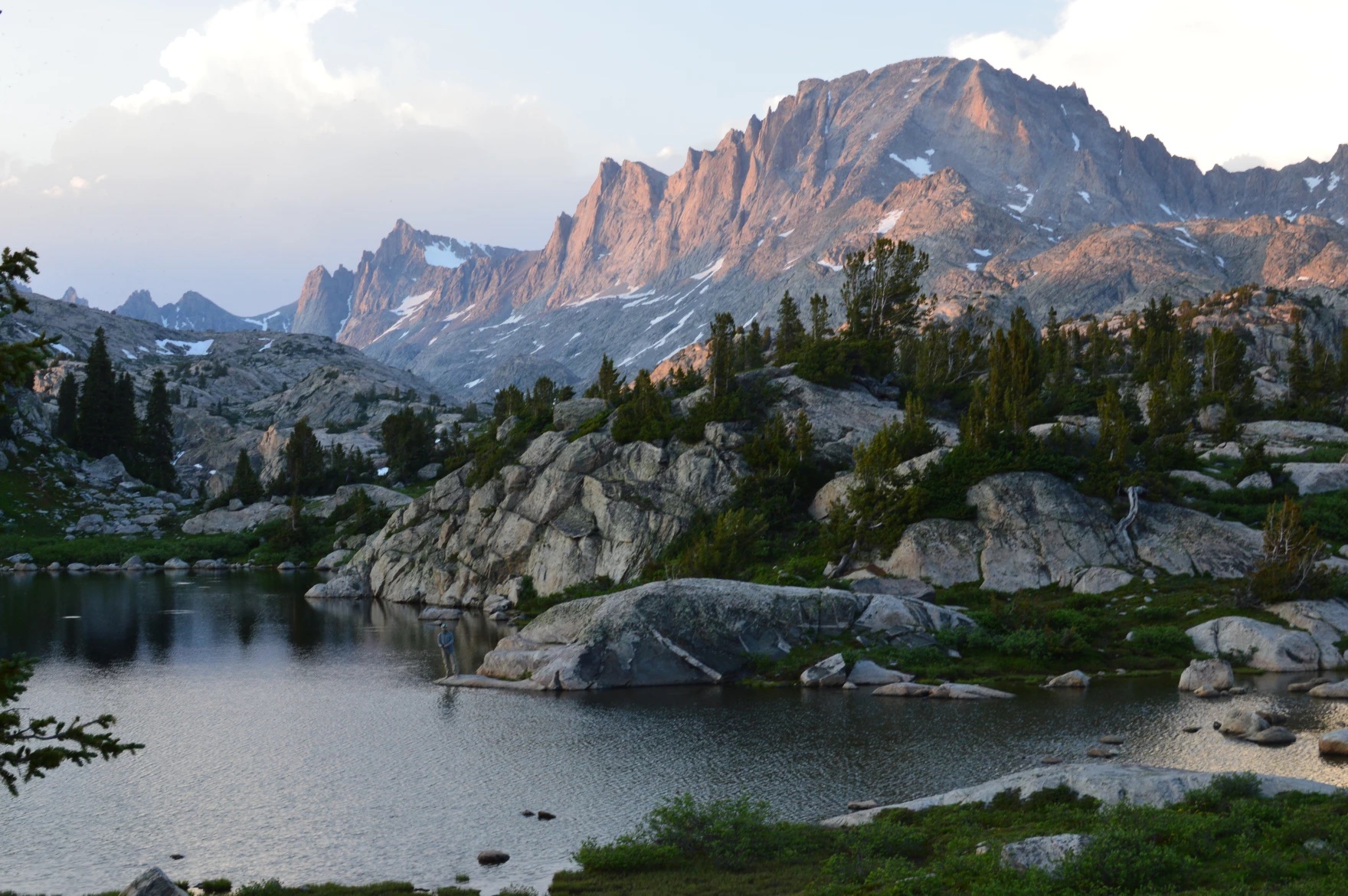 A beautiful mountain range in the background of a lake, where one fisherman stands, fishing.