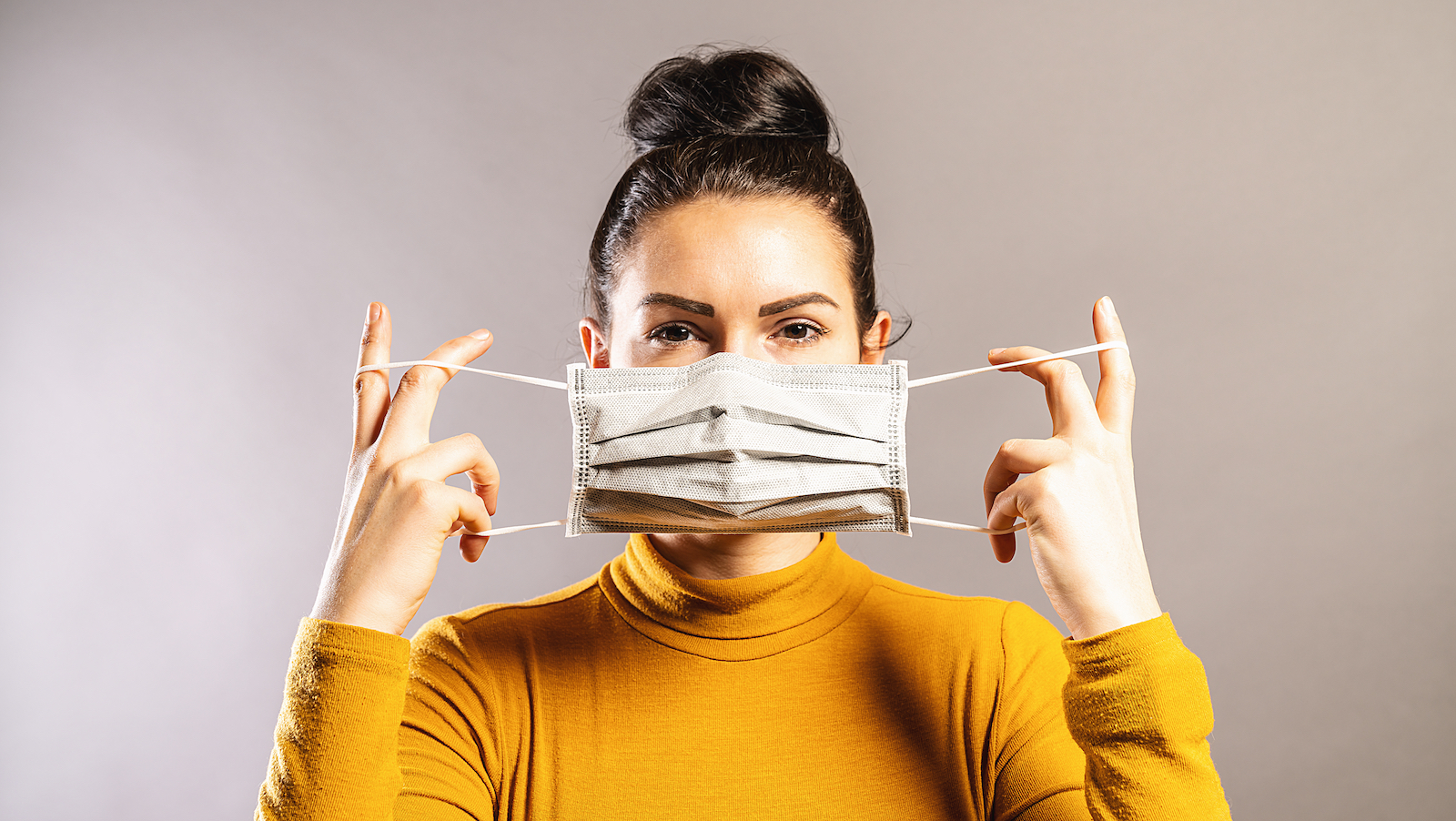 Una mujer poniendo una mascarilla para el COVID 19