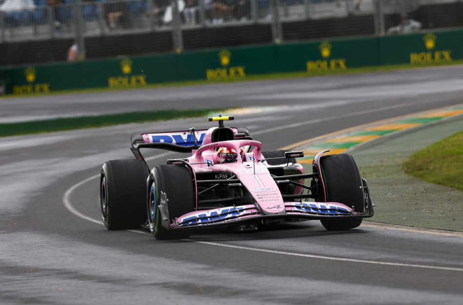 A pink F1 car speeding down a race track