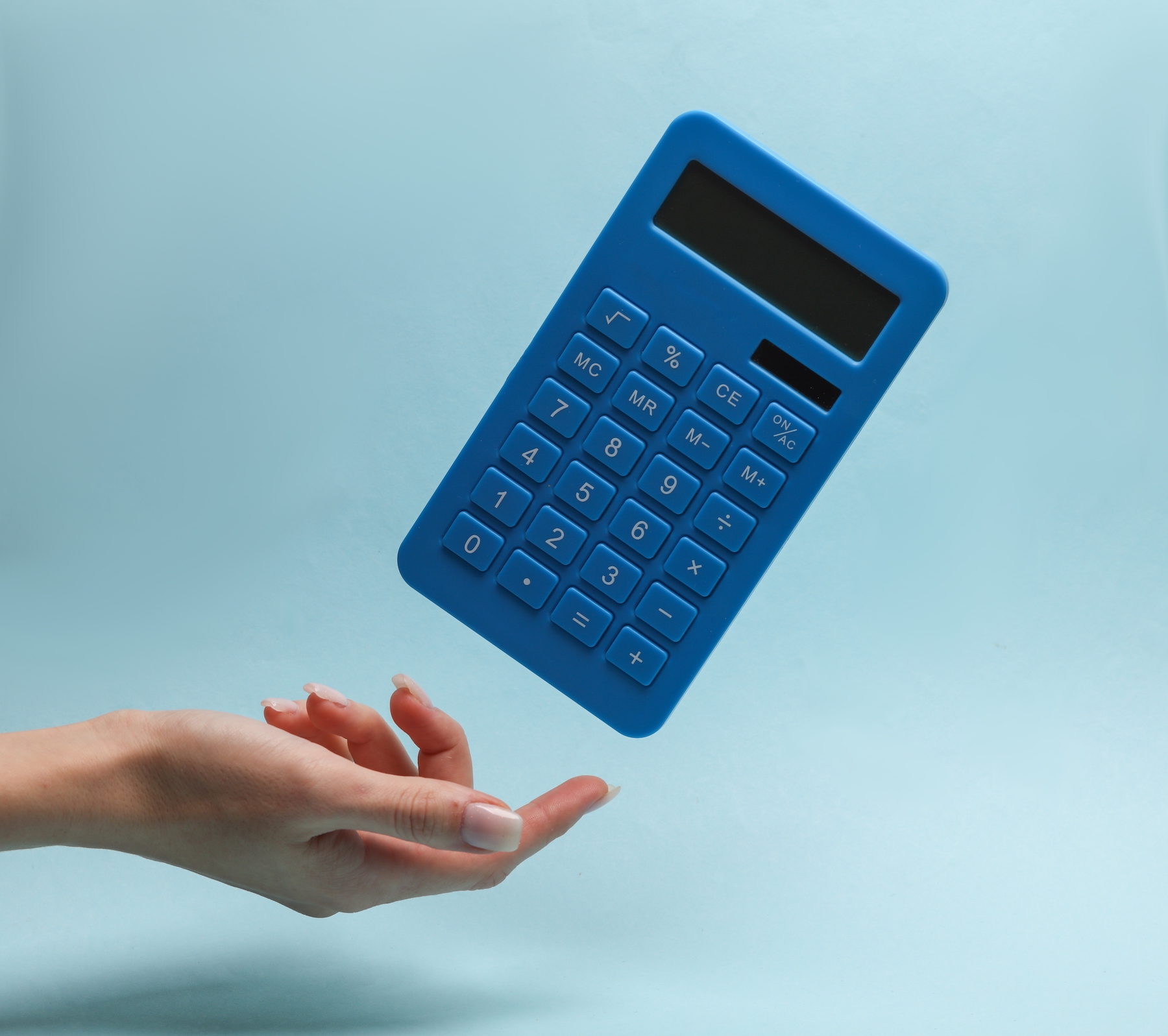 Woman's hand with a levitating calculator on a blue background