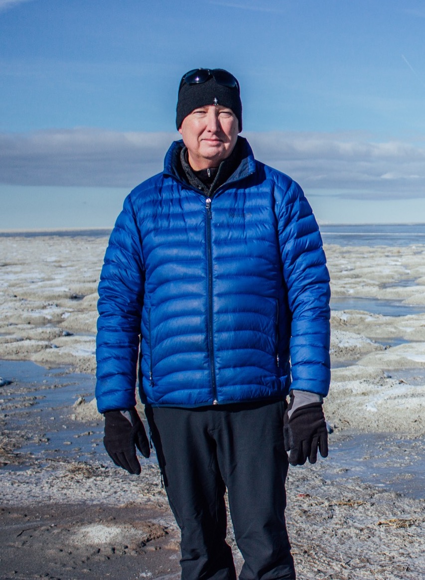 A man in a puffy jacket stands on the dried surface on the Great Salt Lake
