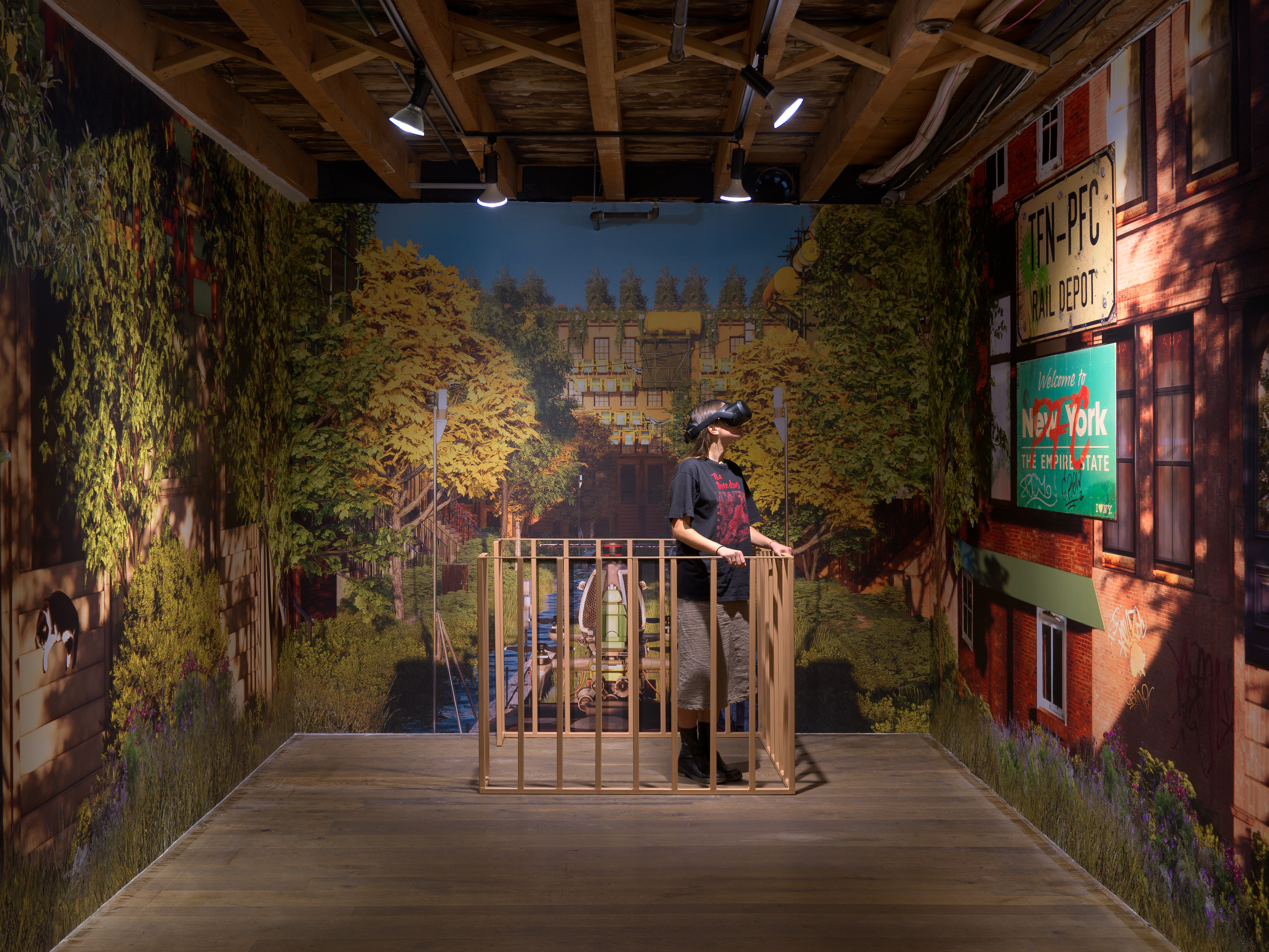 A room with painted walls with trees on them. A person stands in a mini porch with a VR headset on.