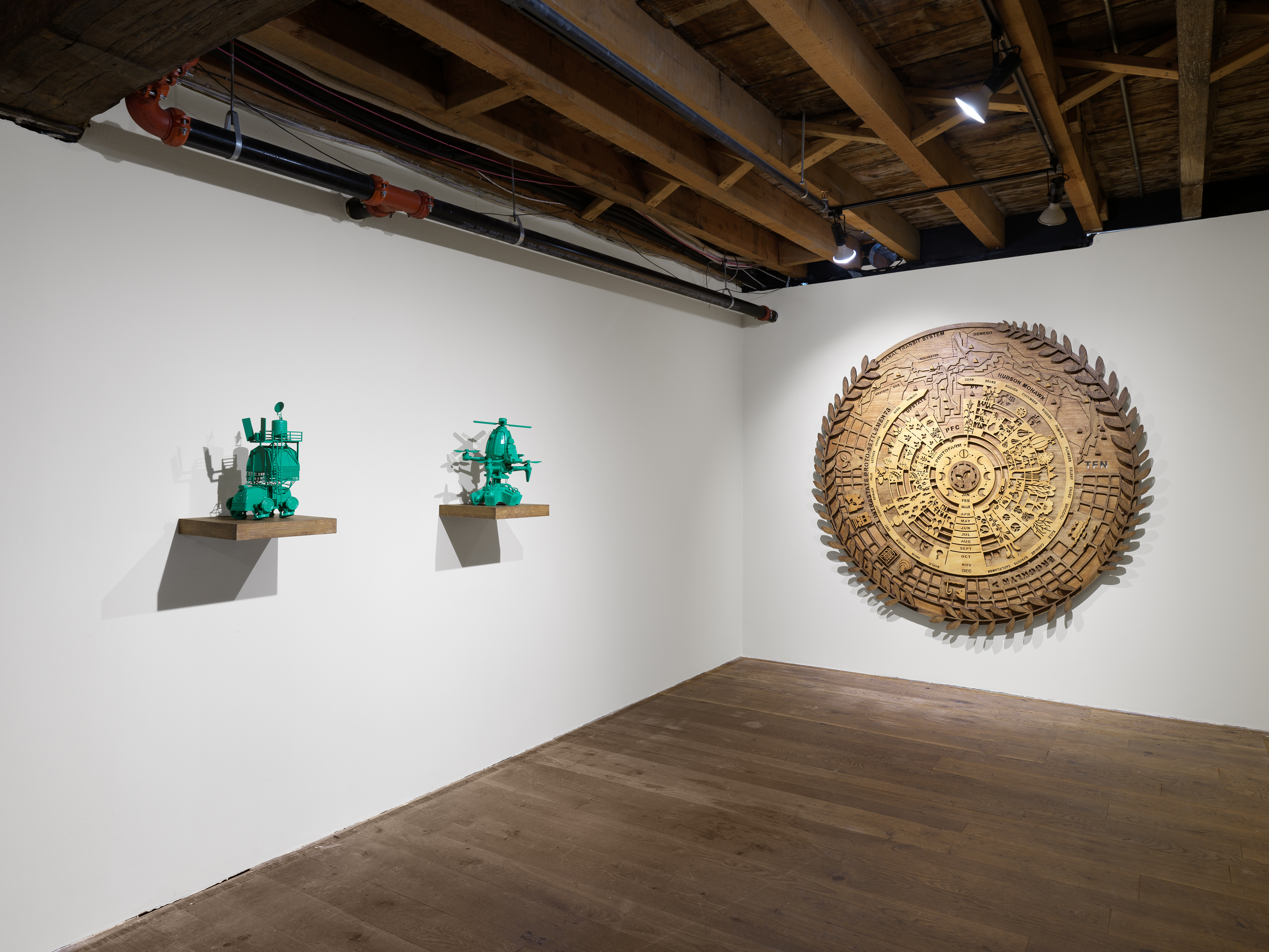 A wooden circular calendar and two small shelves with green sculptures of gardening equipment. 