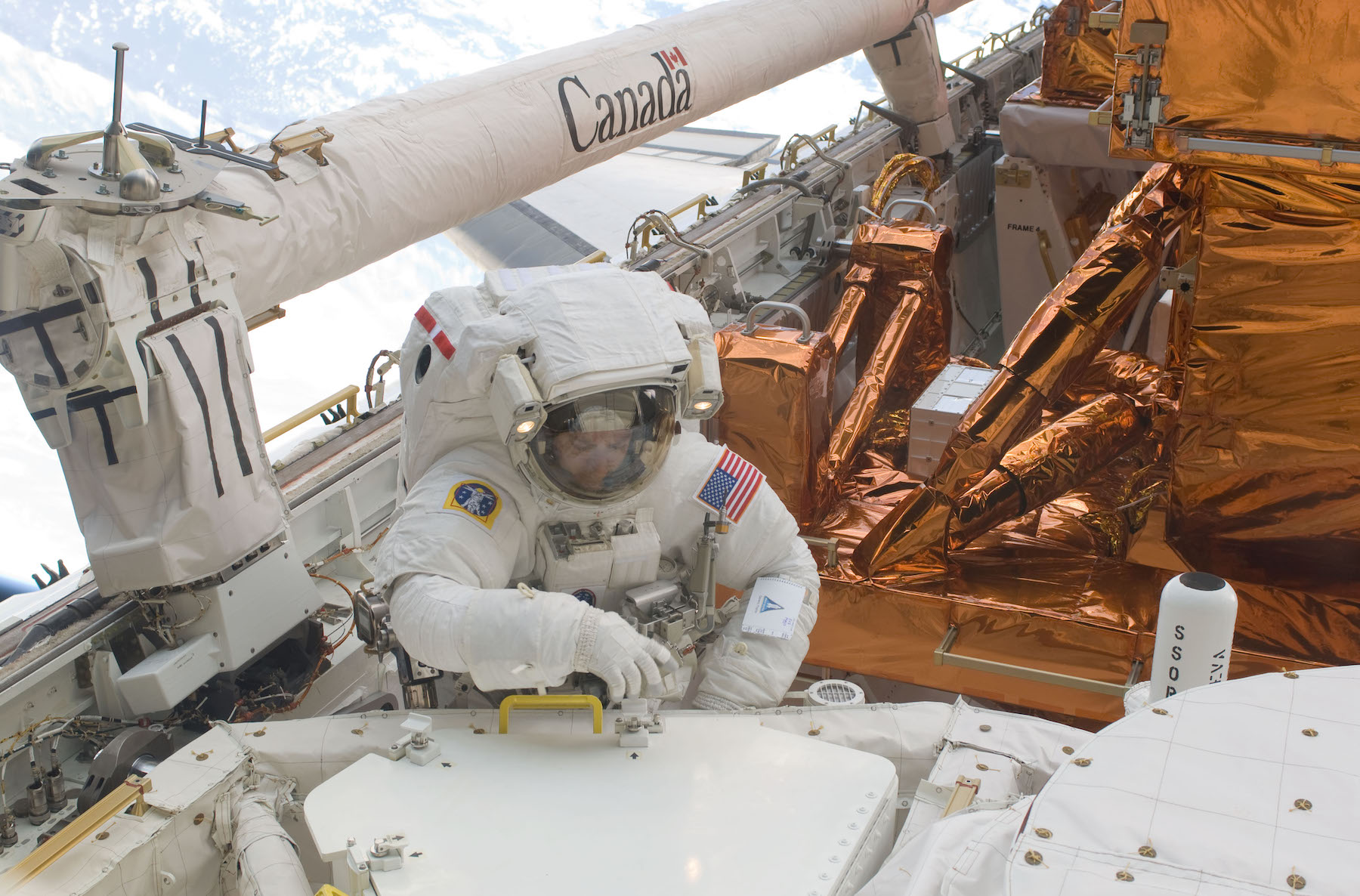 A man in a space suit sits on the roof of a space vessel