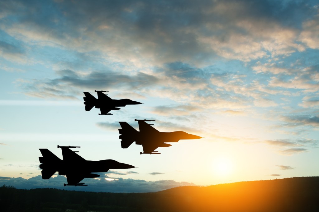 Fighter jet silhouettes on background of sunset.