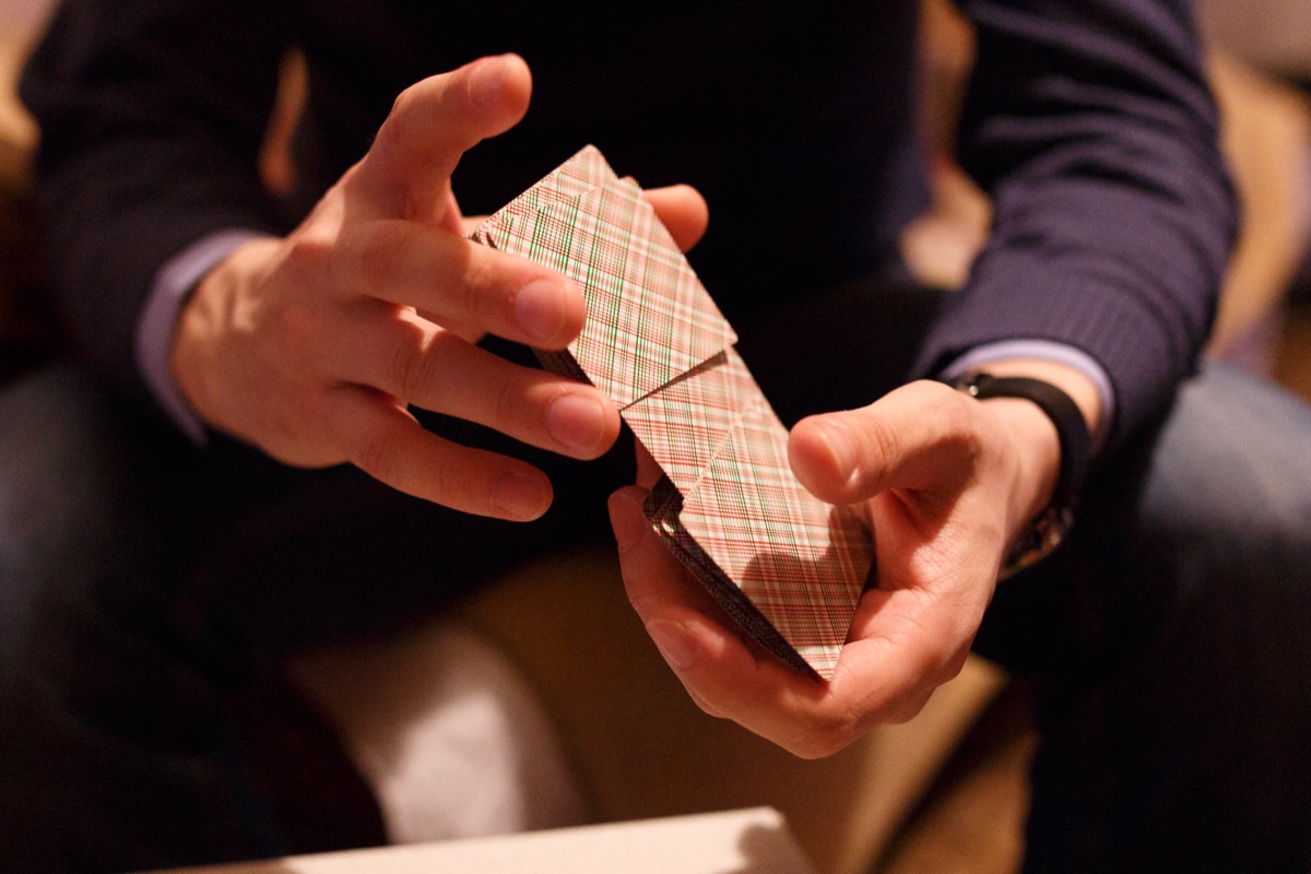 A man is sitting and mixing a deck of cards.