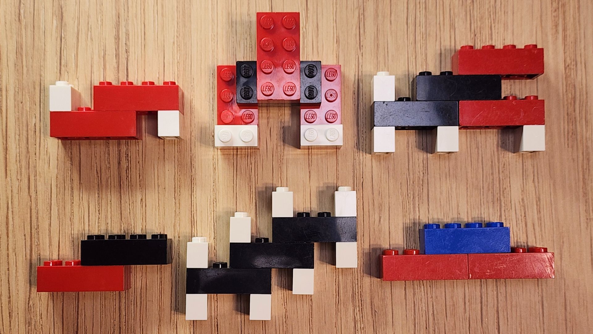 There are six brick molecules pictured. Top left: two red 2x4 bricks with two white 1x2 bricks; top middle: 3 red 2x4 bricks connected by a black 2x4 brick with two 1x2 white bricks; top right: two black 2x4 bricks connected in an offset manner with two red 2x4 bricks attached on the right end and four 1x2 white bricks attached. Bottom left: one red 2x4 brick and one black 2x4 brick connected in an offset manner; bottom middle: three black 2x4 bricks connected in an offset manner to look like stairs with 6 1x2 white bricks at each end on top and bottom; bottom right: two red 2x4 bricks connected by a blue 2x4 brick on top.