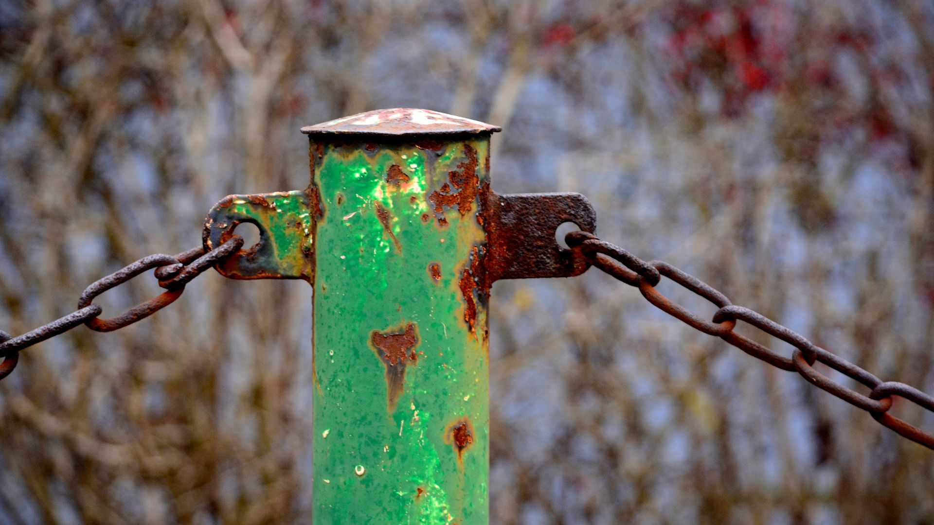 A green pole with an old chain. When the paint has worn away, the metal has turned red.