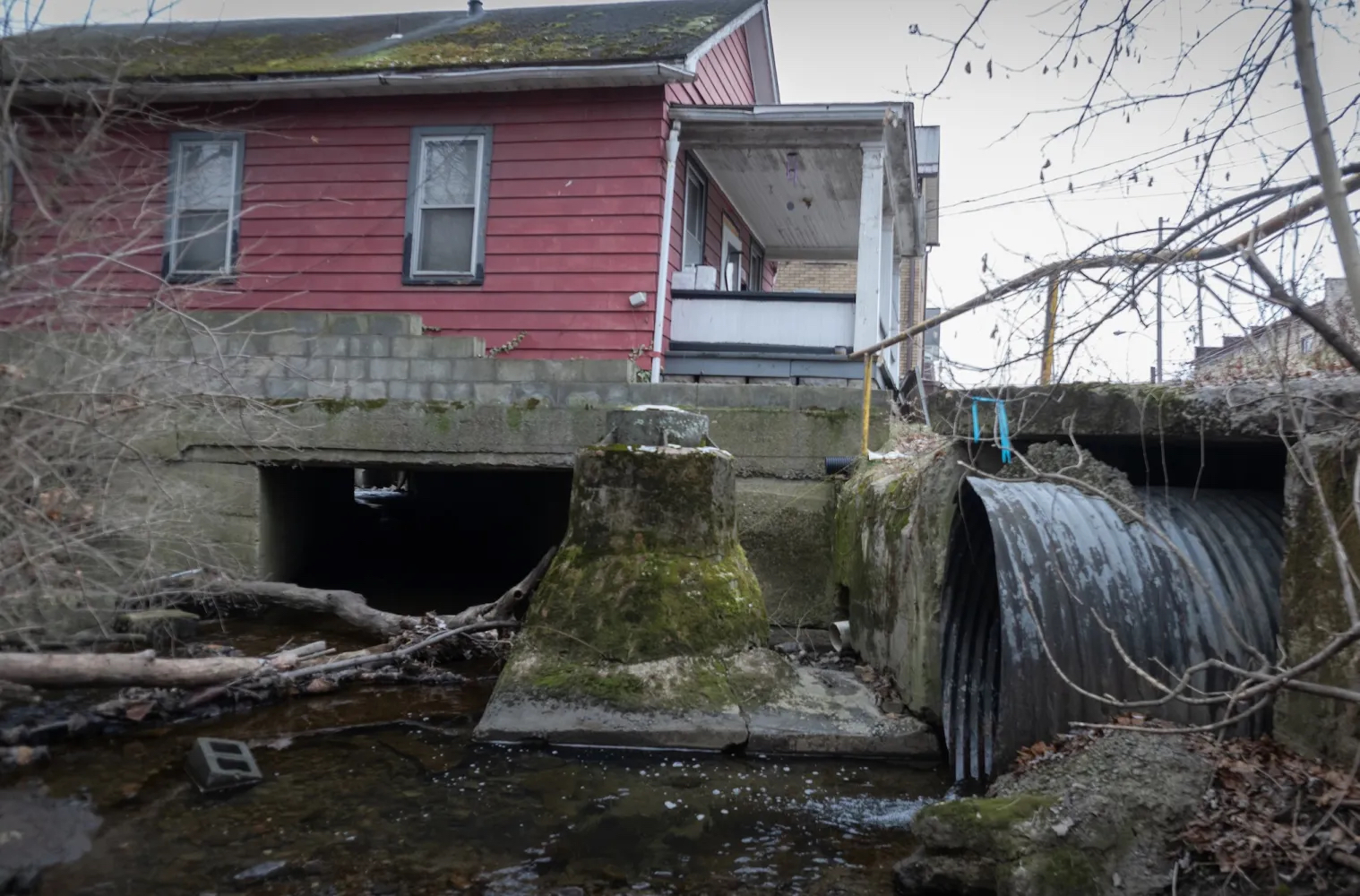 An Appalachian house with a muddy, polluted stream running underneath it.