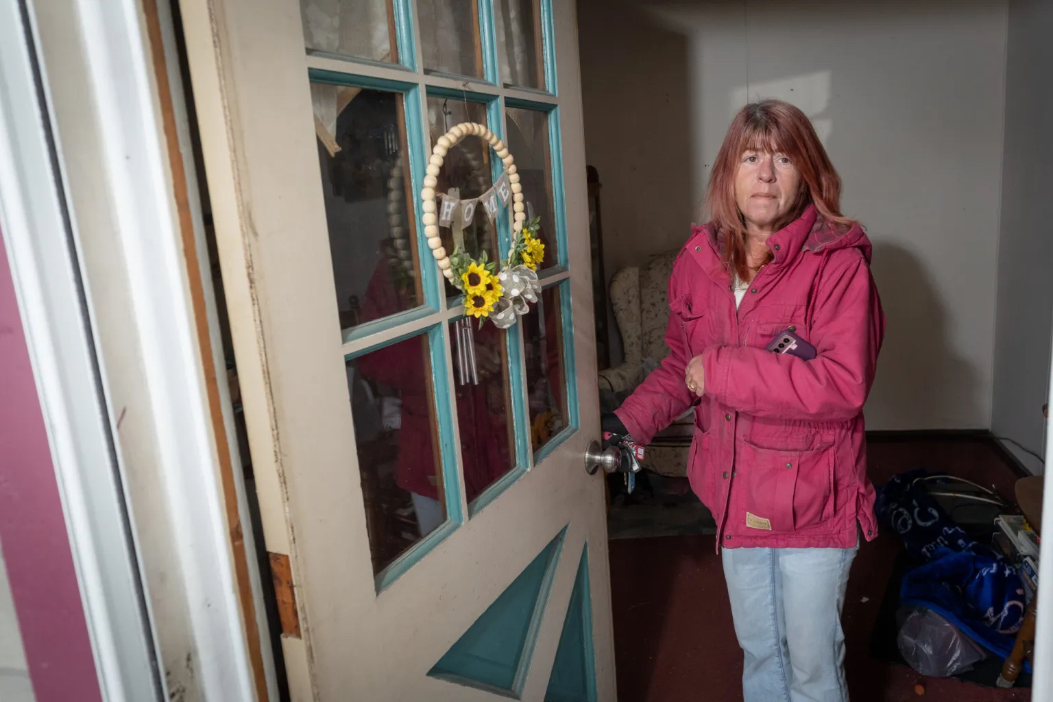 A woman wearing a pink jacket opening her front door.