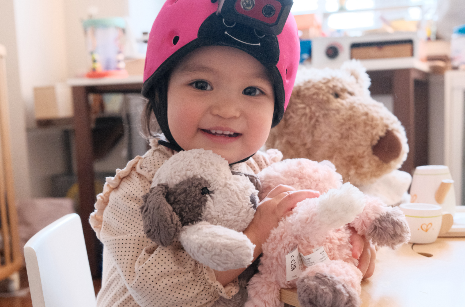 A smiling baby wearing a head camera and holding stuffed animals.