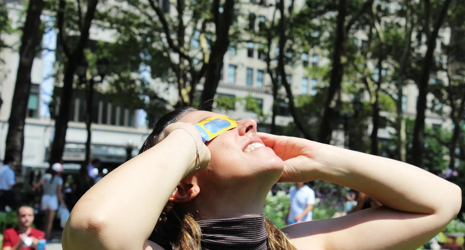 Una mujer mirando al sol con visores solares.