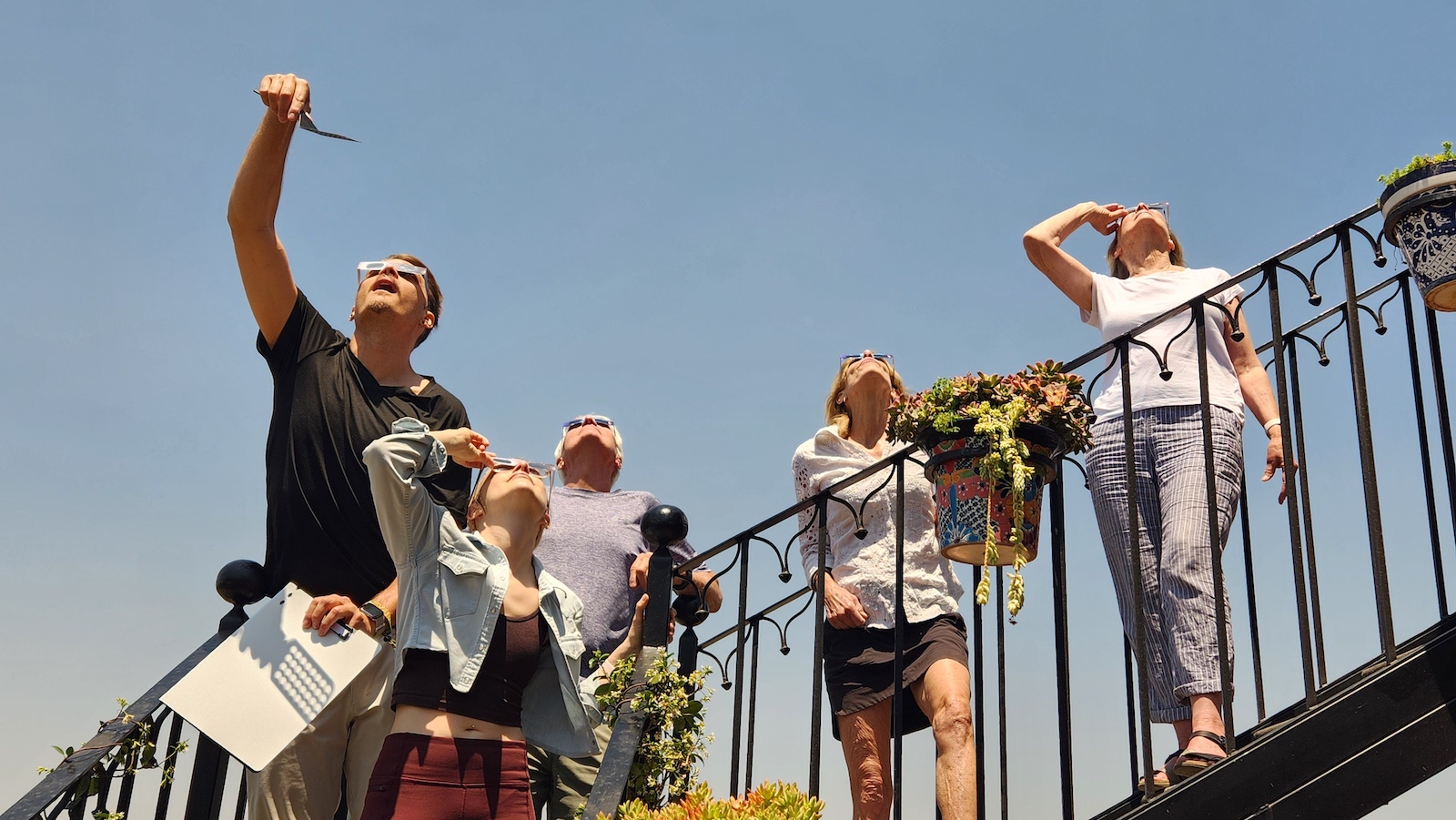 A family wearing eclipse glasses and looking up at the April 8 eclipse.