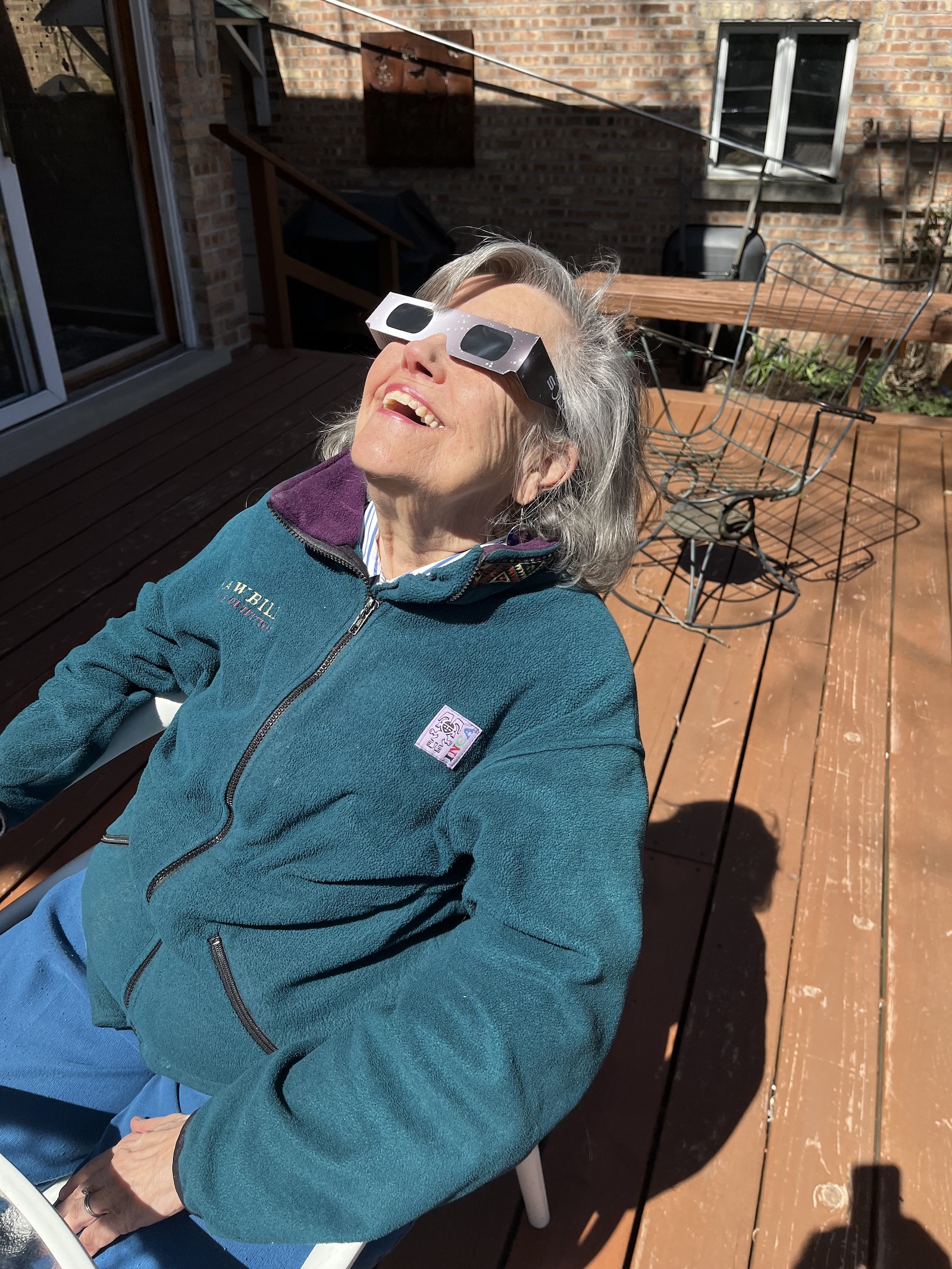 A woman wearing eclipse glasses leaning back in a lawn chair watching the eclipse.