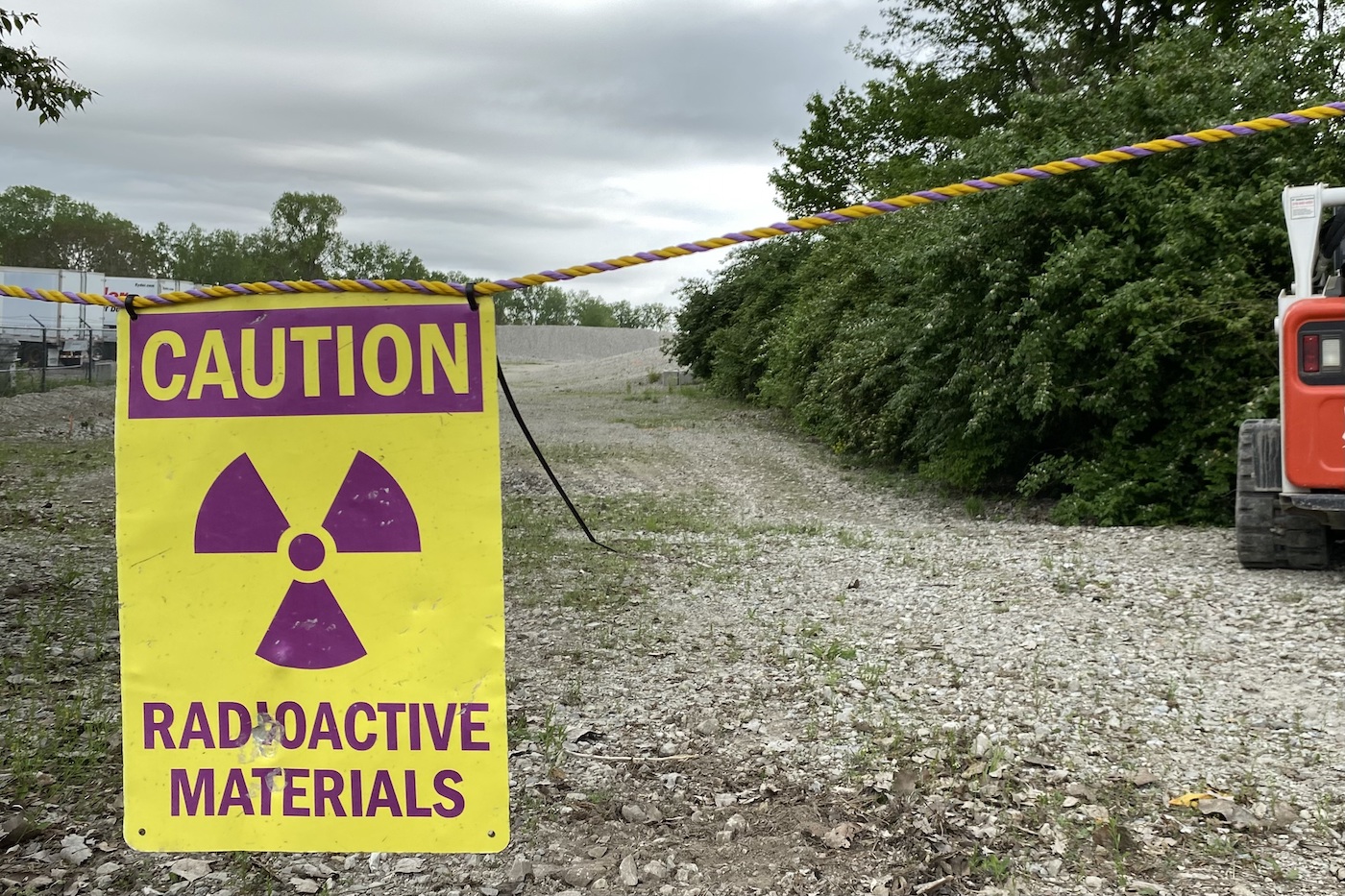 A rope crossing over a dirt road that reads "CAUTION: Radioactive Materials"