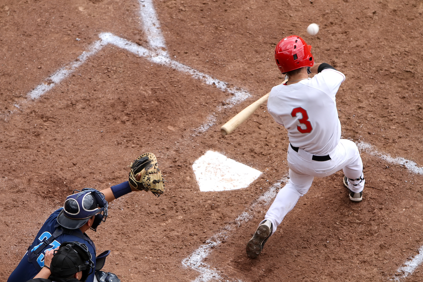 A baseball player swinging at a ball on home base.