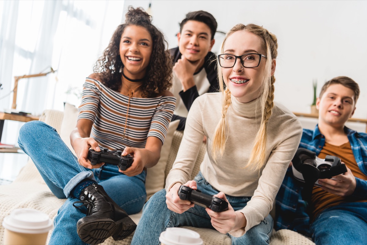 Happy teens play a video game together.