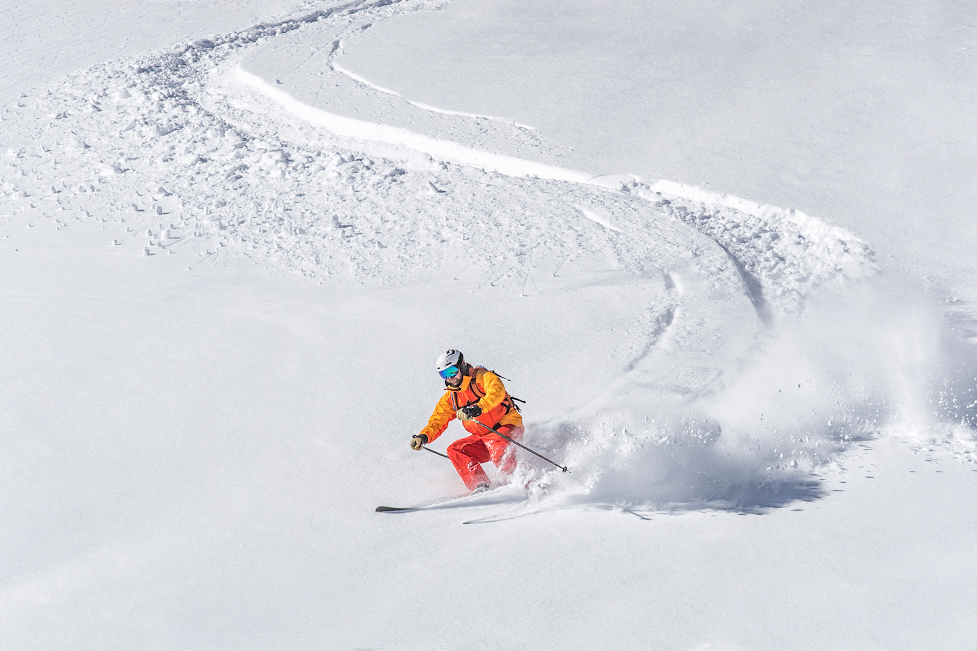 one freeride skier skiing downhill trough deep fresh powder