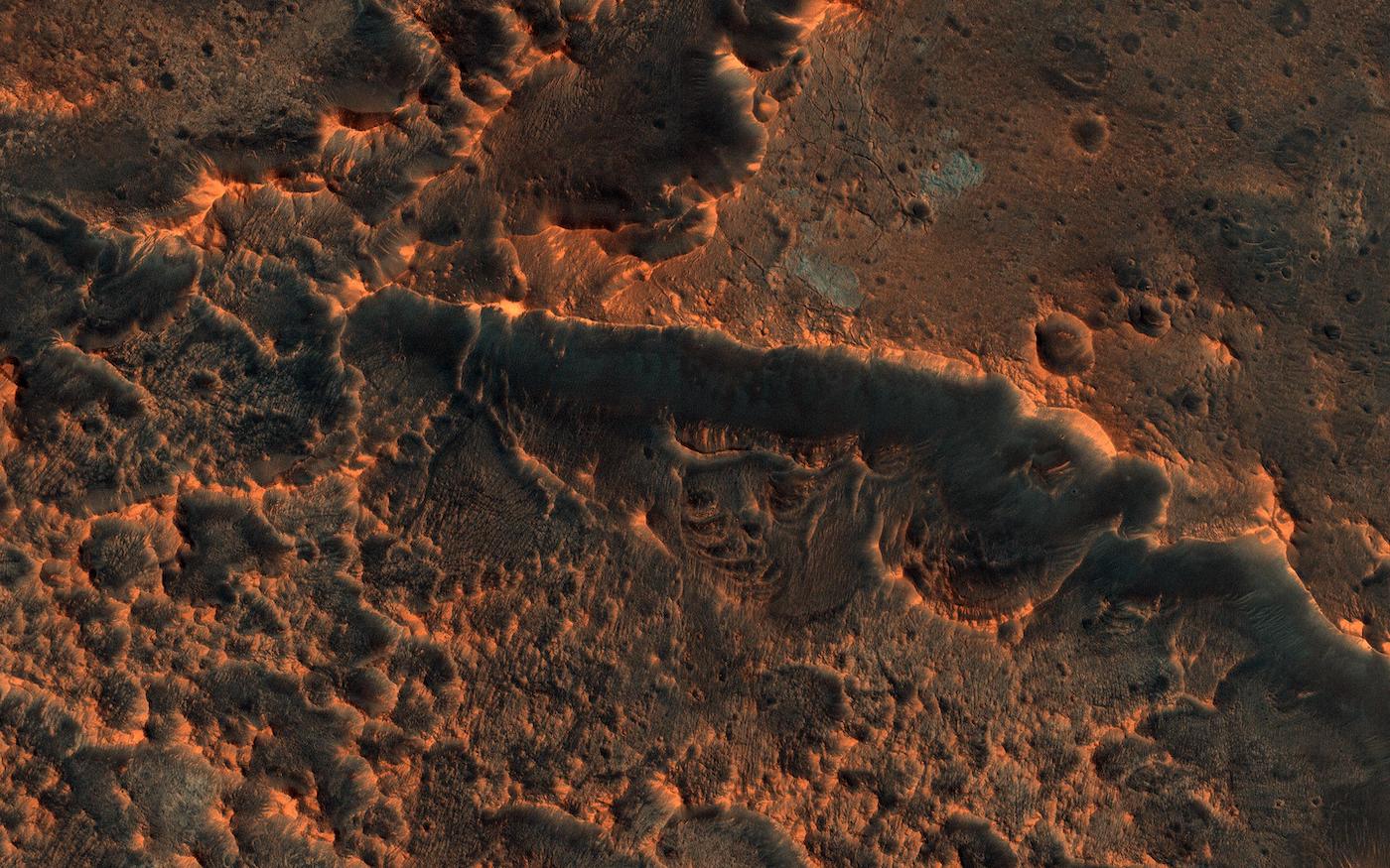 A bumpy red land surface, covered in craters.