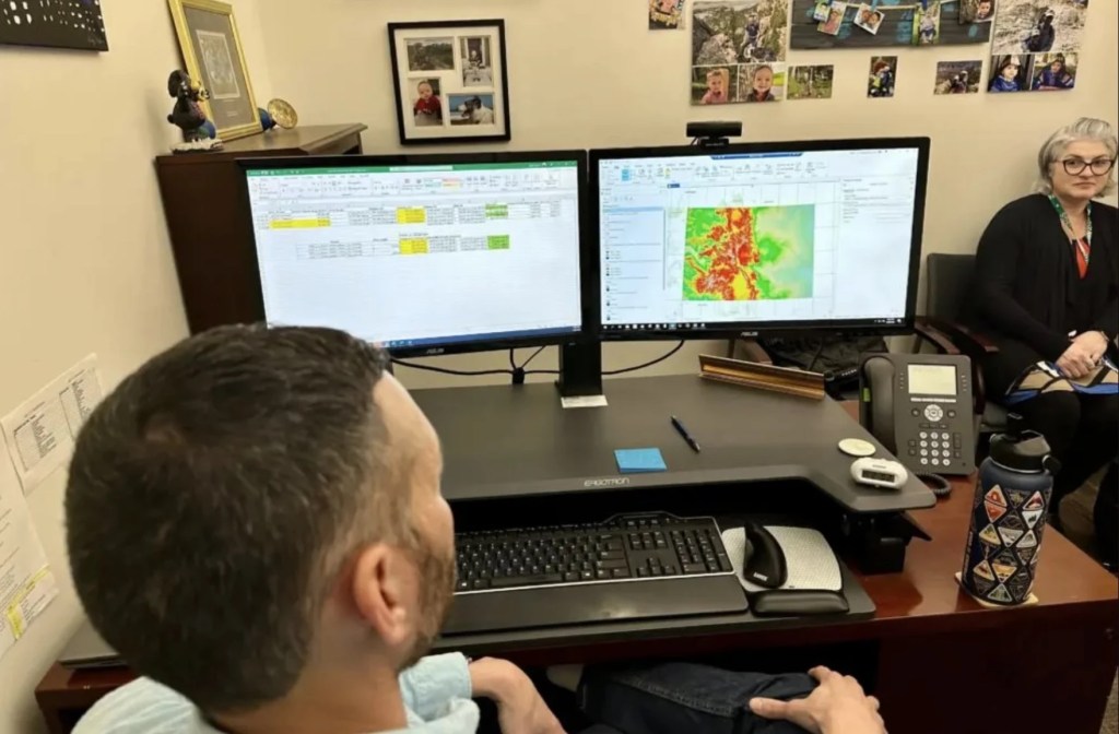 A person at a desk with two monitors.