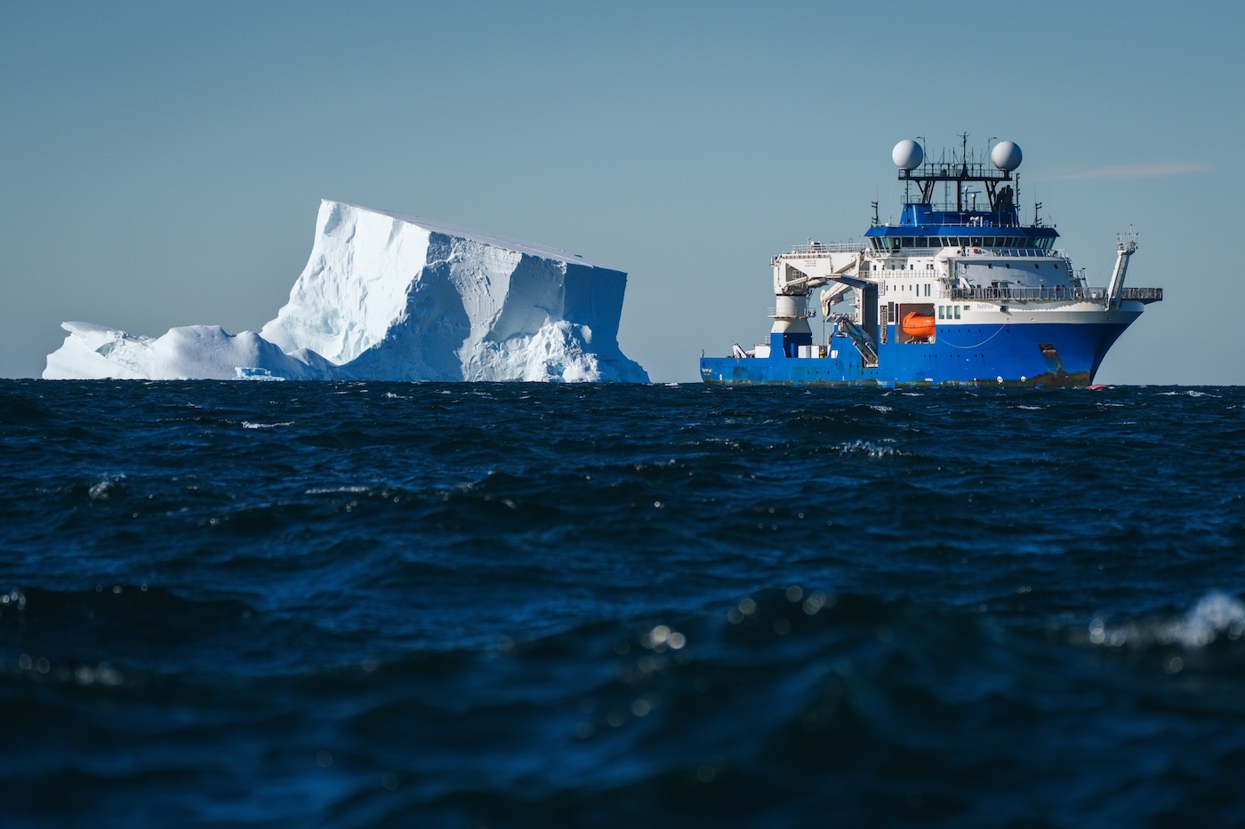 A ship next to a large iceberg floating in the ocean