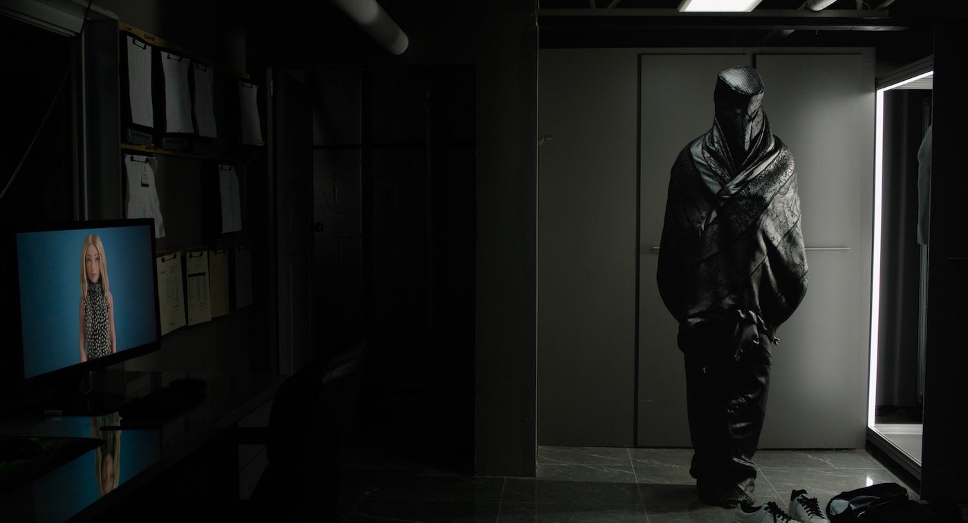 A person standing wearing a full body coverage grey fabric wrap that covers his face.