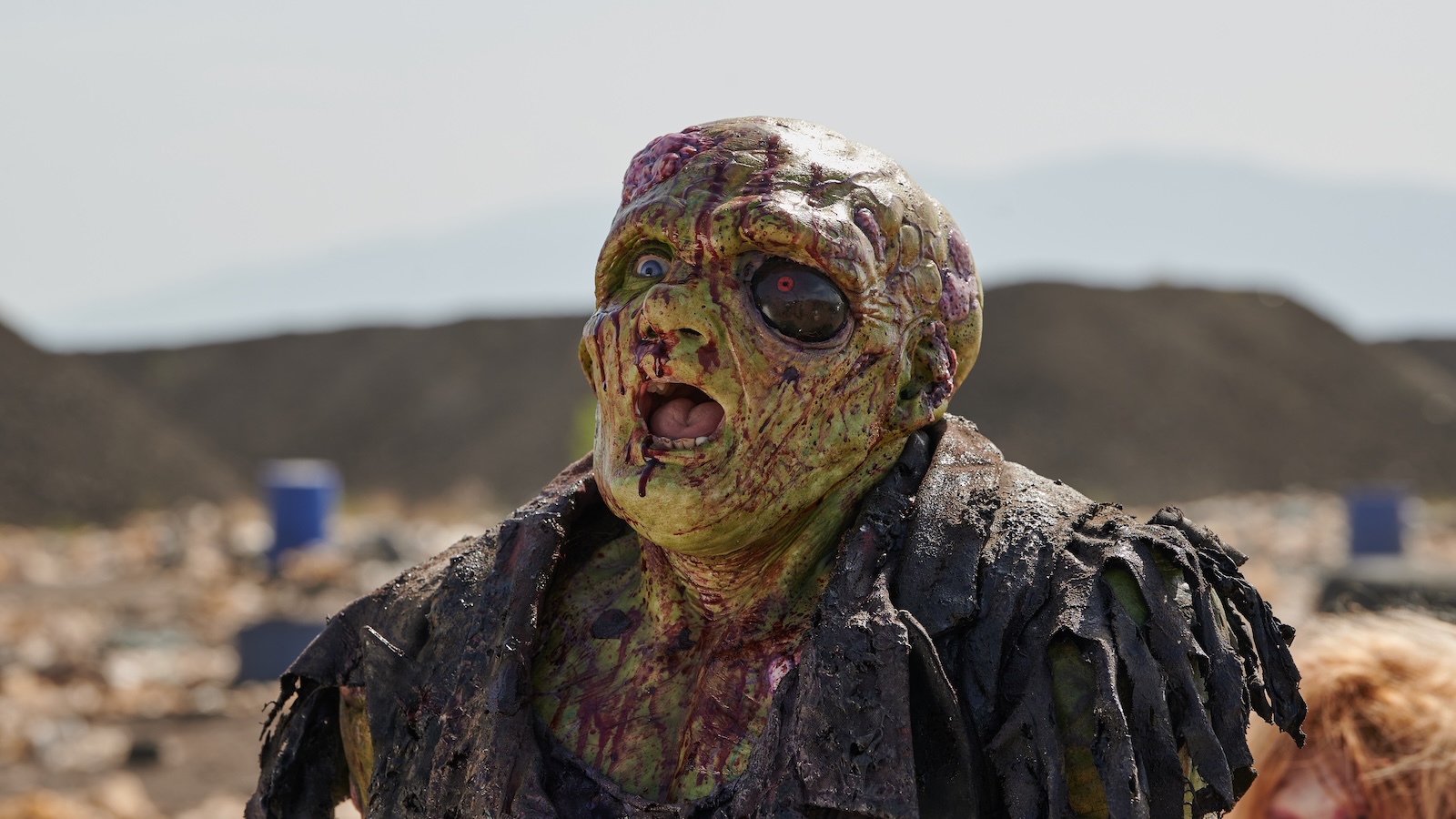 A green man with a giant black eye covered in blood and screaming.