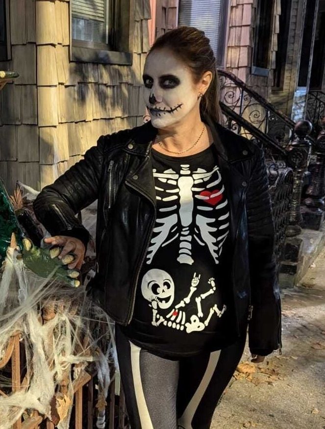 A woman dressed as a skeleton, with a baby skeleton on her stomach.