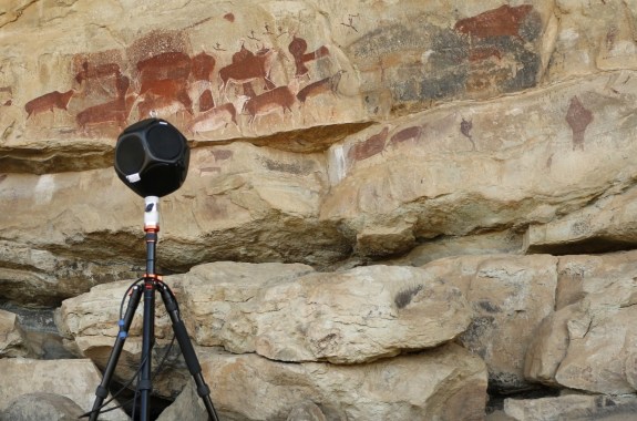 A speaker set up next to a cave with ancient art painted onto it. Archaeology