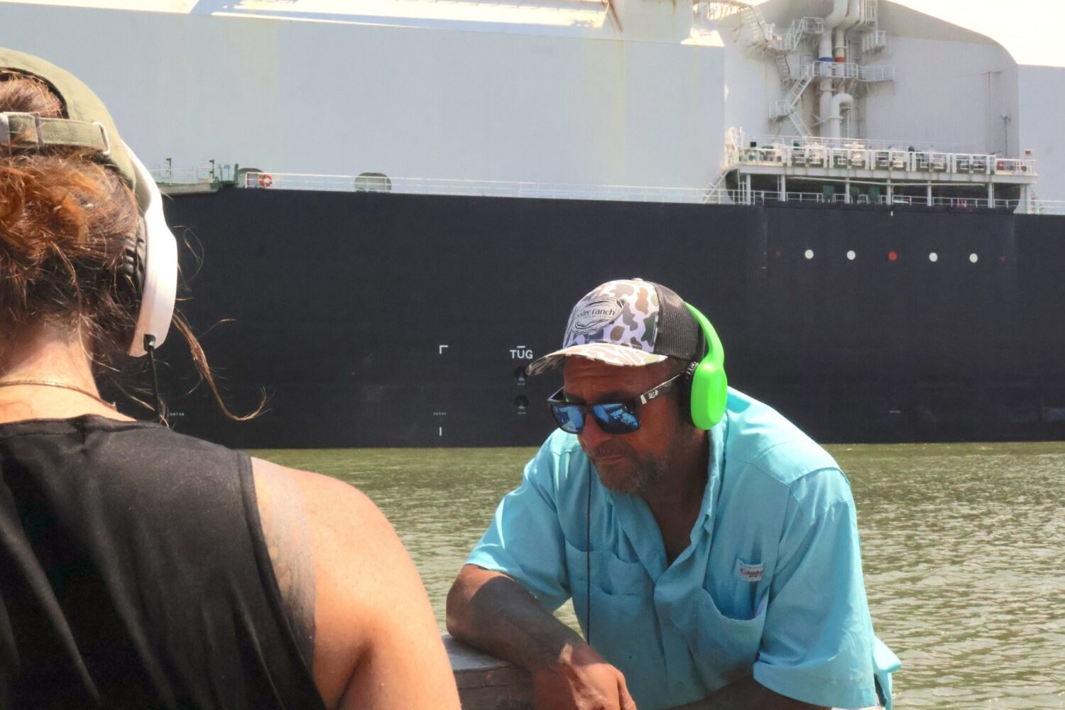 A man and a woman with headphones on listen as
