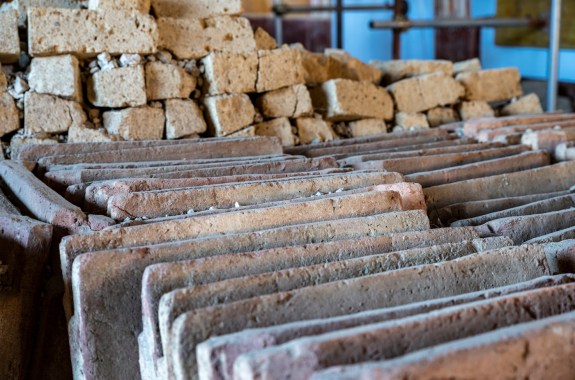 Beige ceramic tiles standing up like books against a pile of concrete blocks.