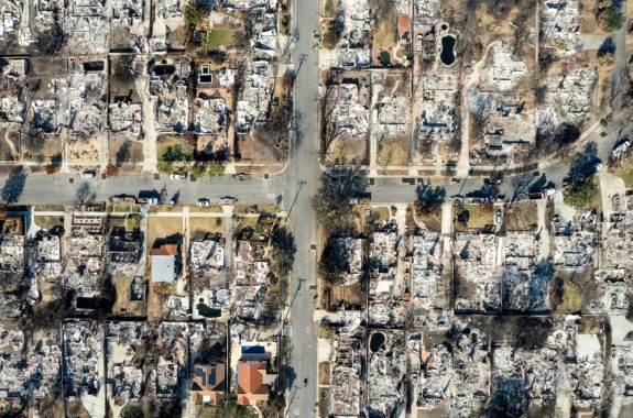 An aerial photograph shows blocks of burned houses and grayish debris.