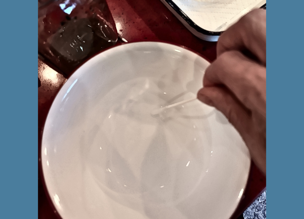 A cotton swab being dipped in a bowl of water