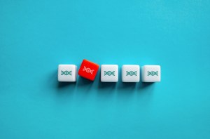A row of white dice with small DNA illustrations. One red die with DNA is offset from the line.