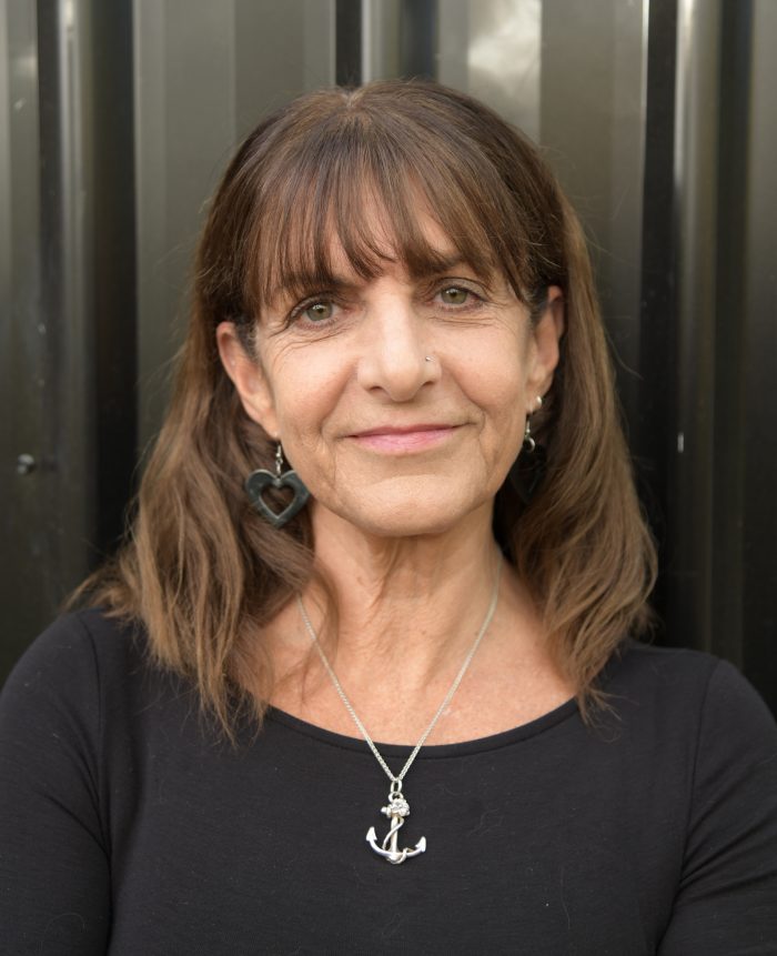 A woman with shoulder length brown hair and a black shirt on smiles at the camera.