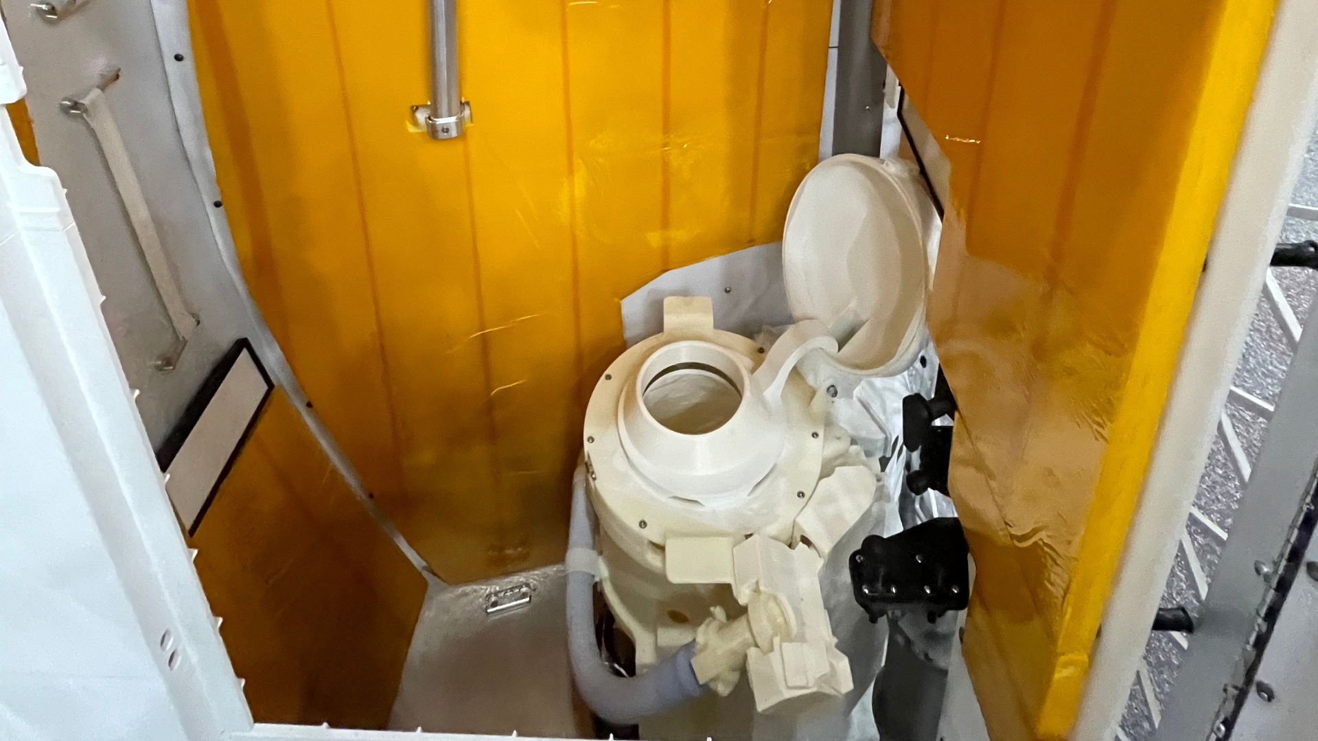 A modified toilet in a small yellow room.