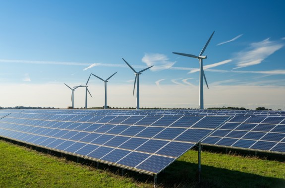 a row of wind turbines with solar panels in the foreground