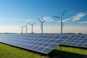 a row of wind turbines with solar panels in the foreground