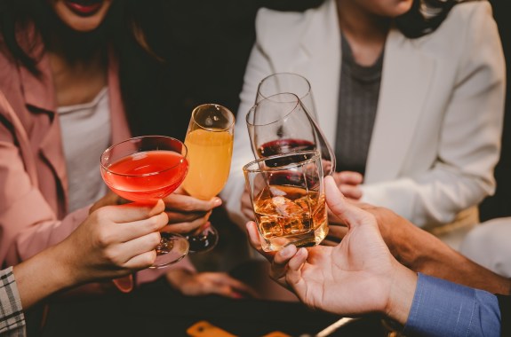 Close-up of four different cocktails held together for a toast.