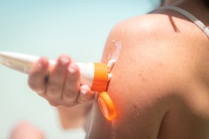 Close-up of suncreen being squeezed from a tube onto a bare shoulder