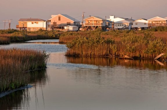 The sun sets on a row of houses along Louisiana Highway 1 in Grand Isle, Louisiana.