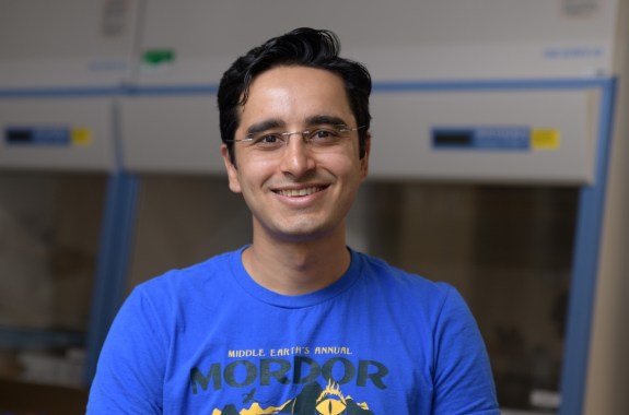A man in a blue T-shirt smiles at the camera