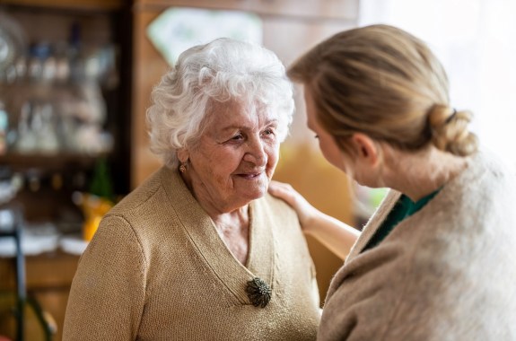 A health care worker talking to a senior woman with white curly hair