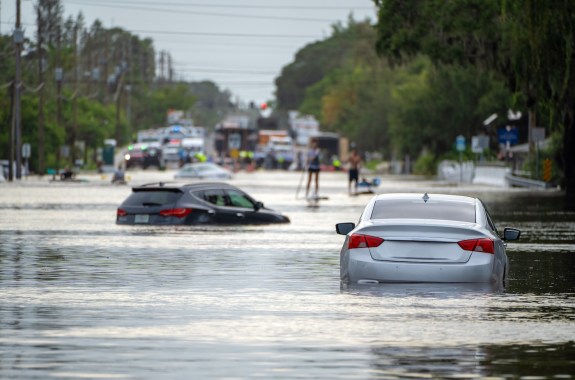 Two cars are partially submerged in water on a street.