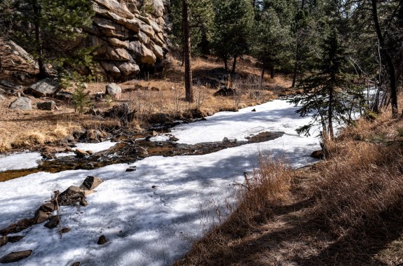 A strip of ice and rock runs through a dry, grassy landscape