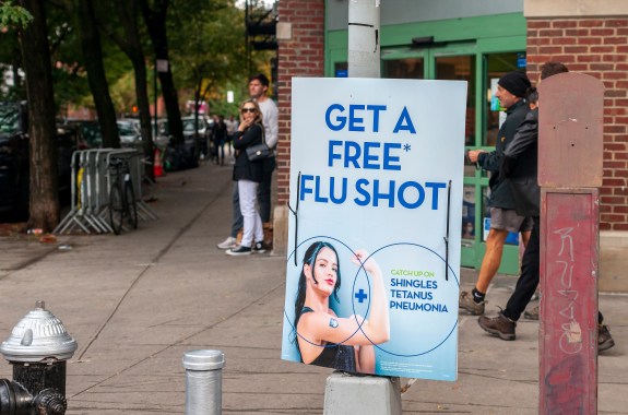 A sign with a woman holding arm up encouraging flu shots.