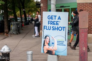 A sign with a woman holding arm up encouraging flu shots.